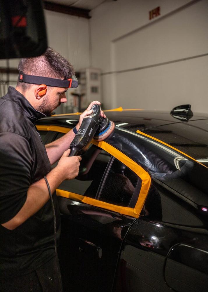 Obsidian detailer applying paint protection film to a hood