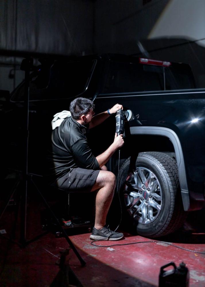 Obsidian detailer machine-buffing the paint on a black truck during correction in Baltimore